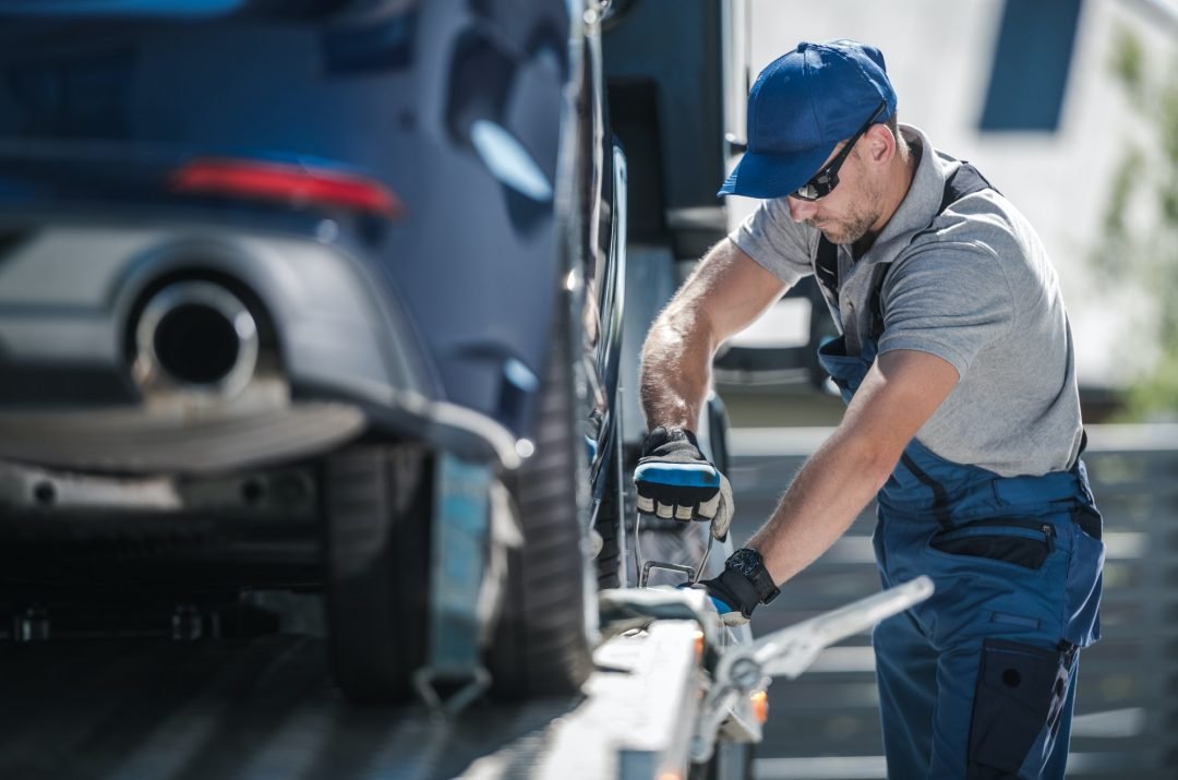 Operator securing a car on a tilt tray tow truck